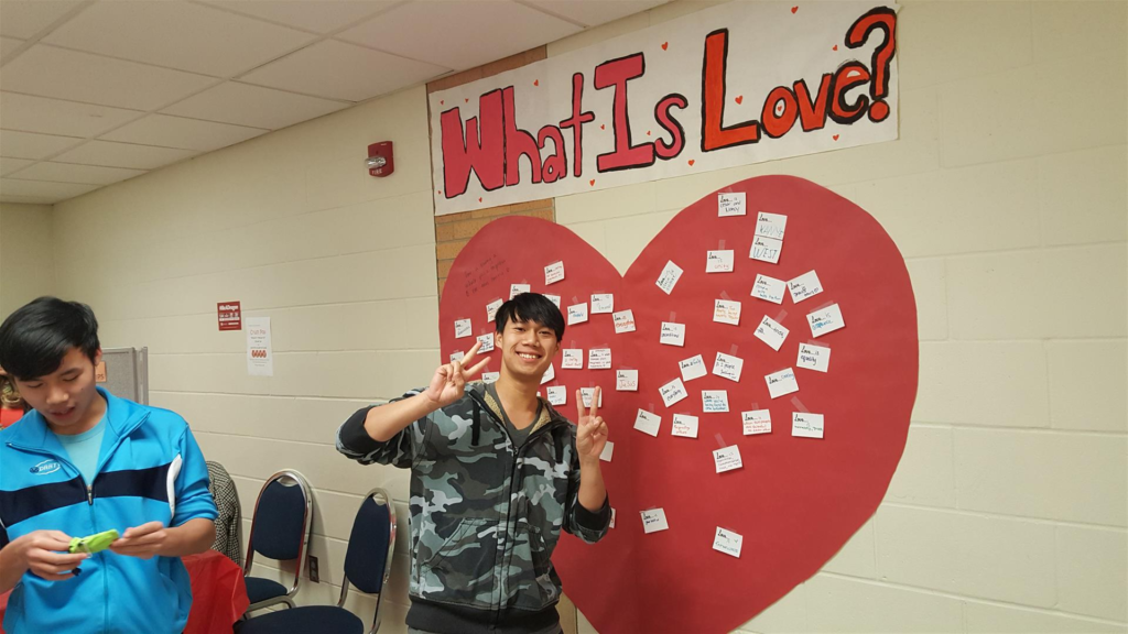 Student posing in front of "What is Love" wall art