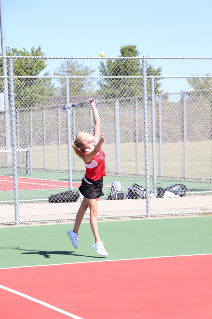 Trojan tennis player reaching high for the hit