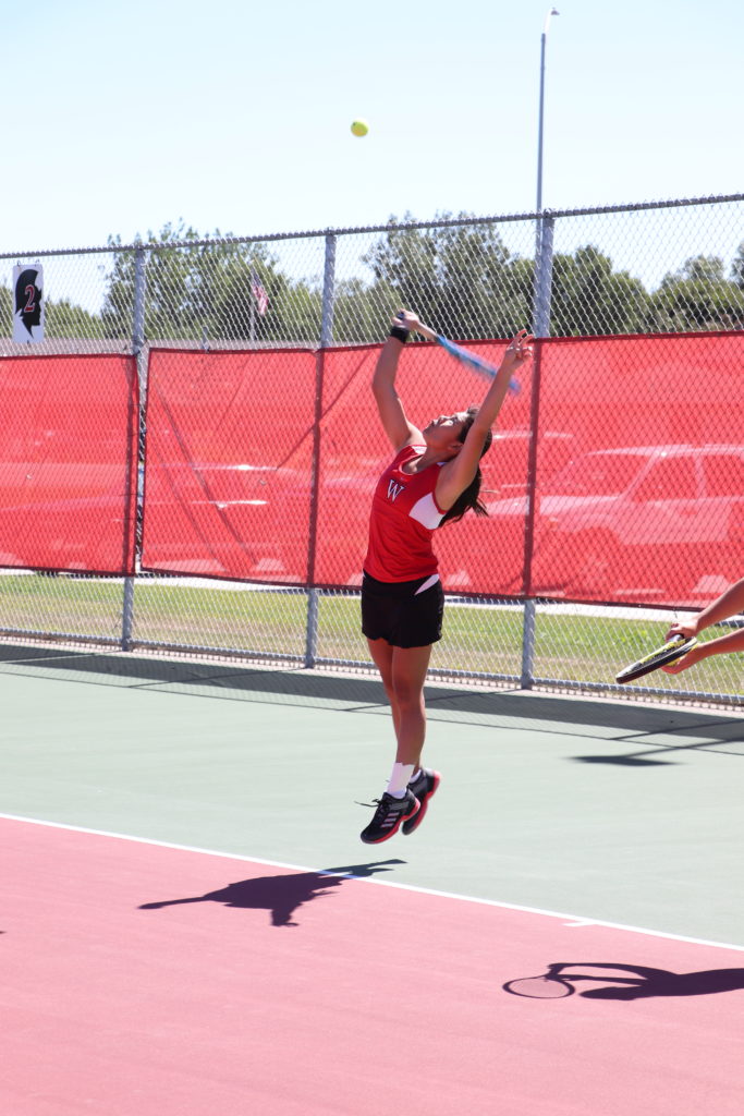 Trojan tennis player reaching high