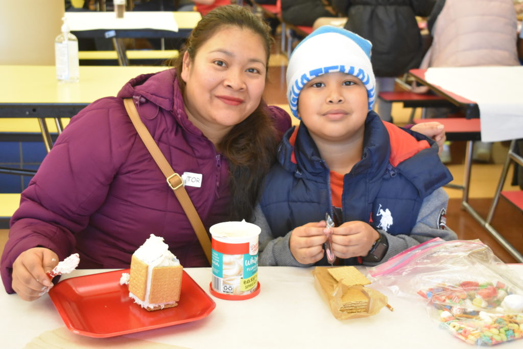 Student and Parent creating a gingerbread house