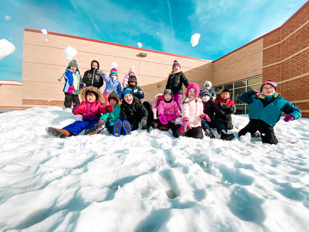 Students on a snowpile throwing snowballs