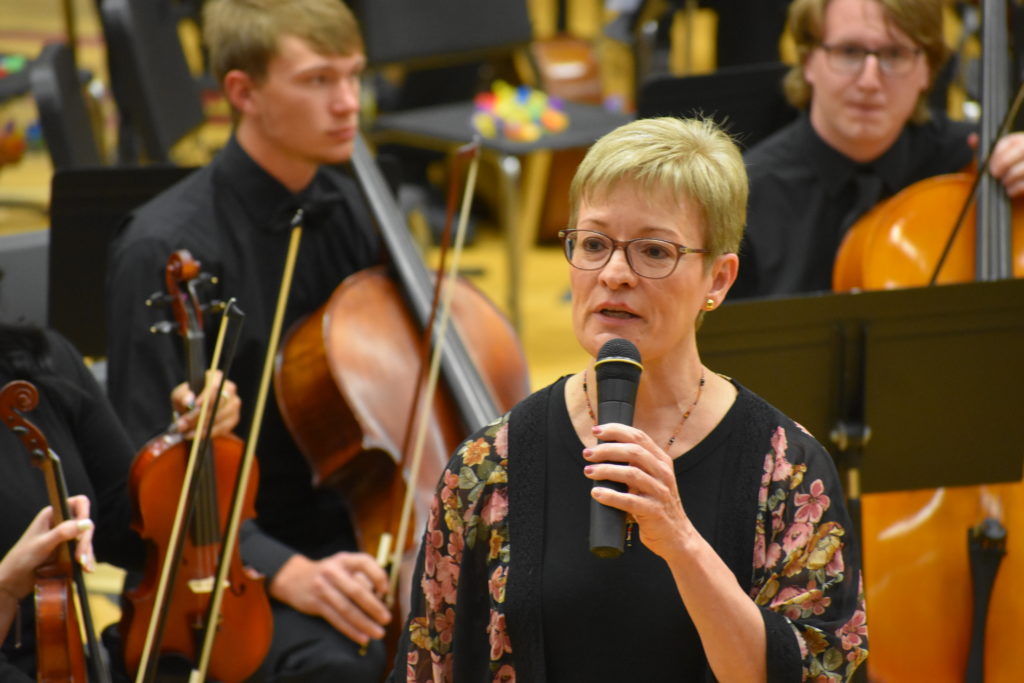 Mrs. Loy speaking with orchestra in the background