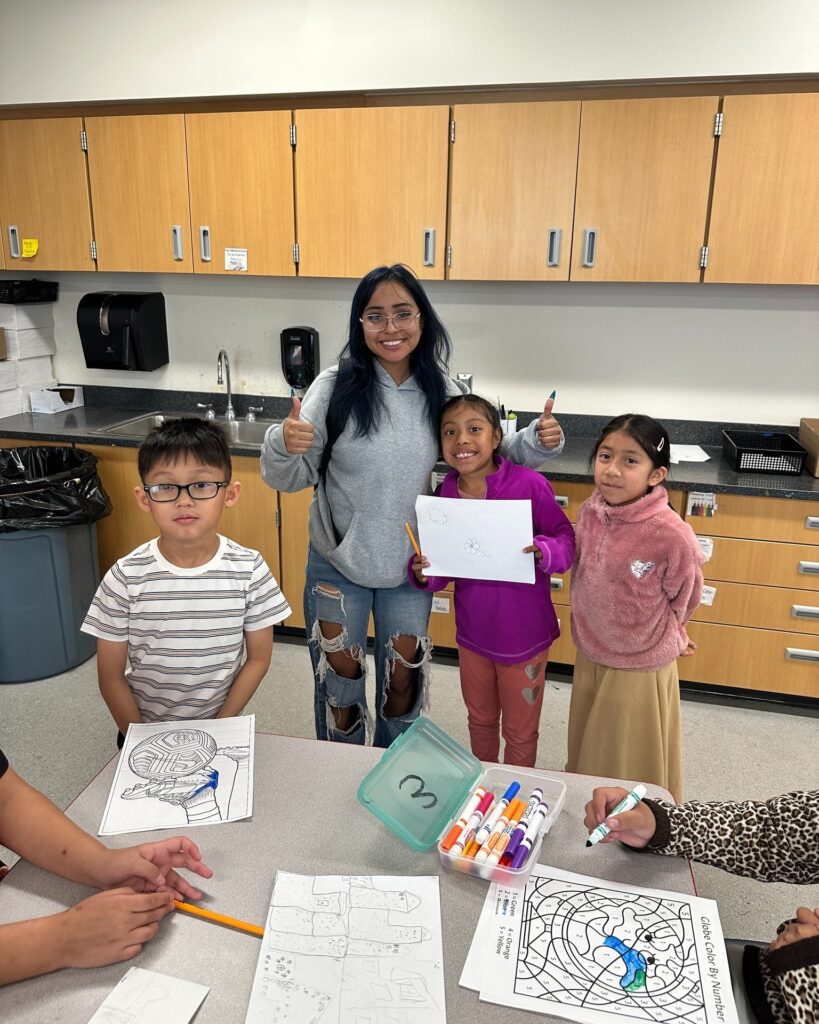 High school student with three elementary students at art station