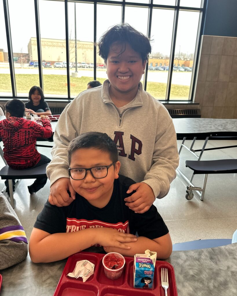 High school student and elementary student at lunch