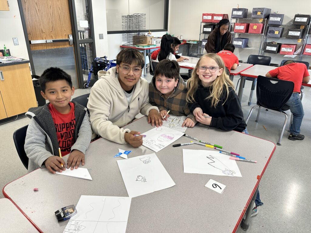 High school student with three elementary students at coloring station