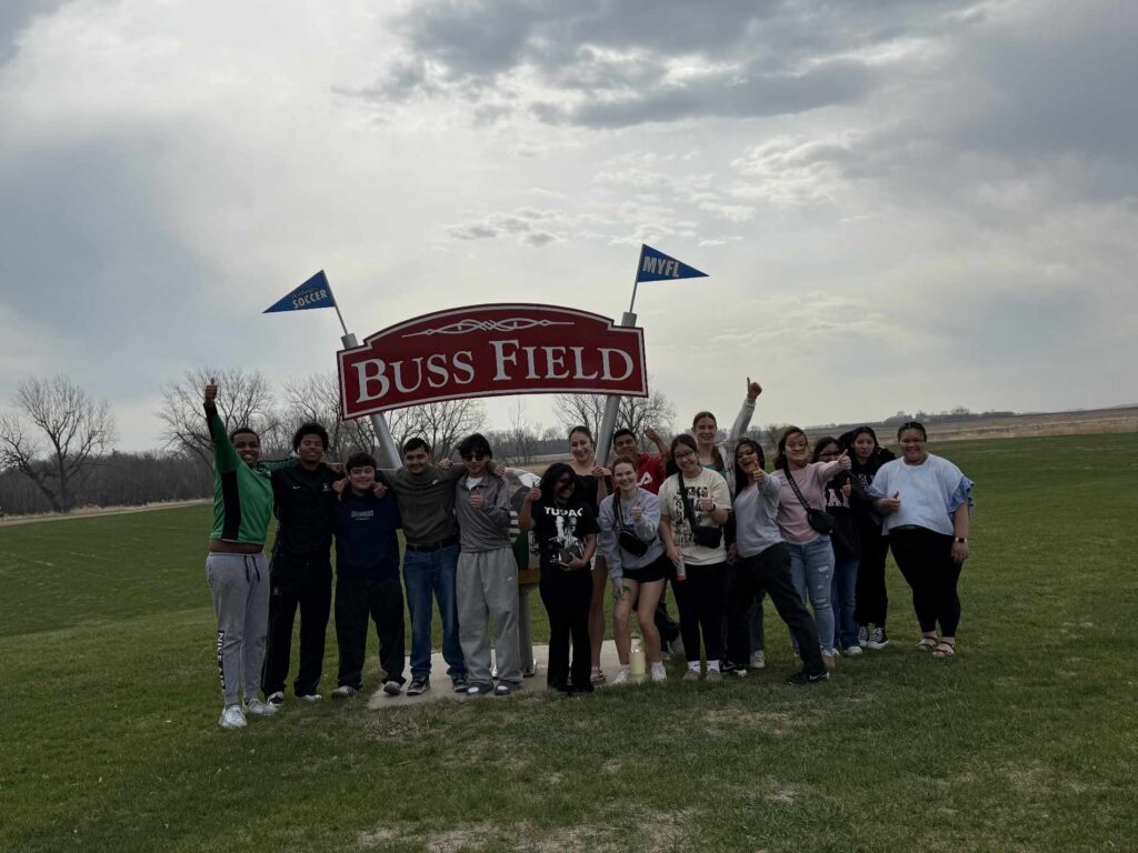 16 Students standing in front of Buss Field sign