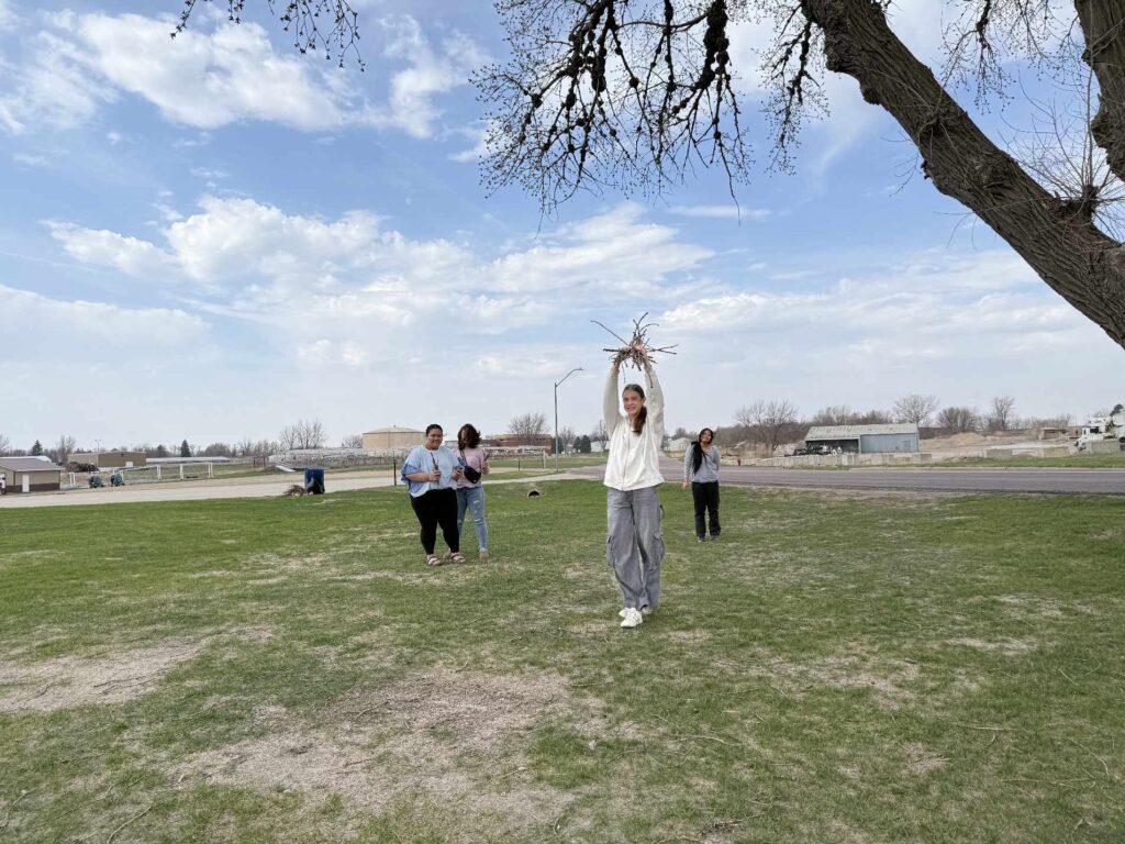4 students picking up sticks at the field