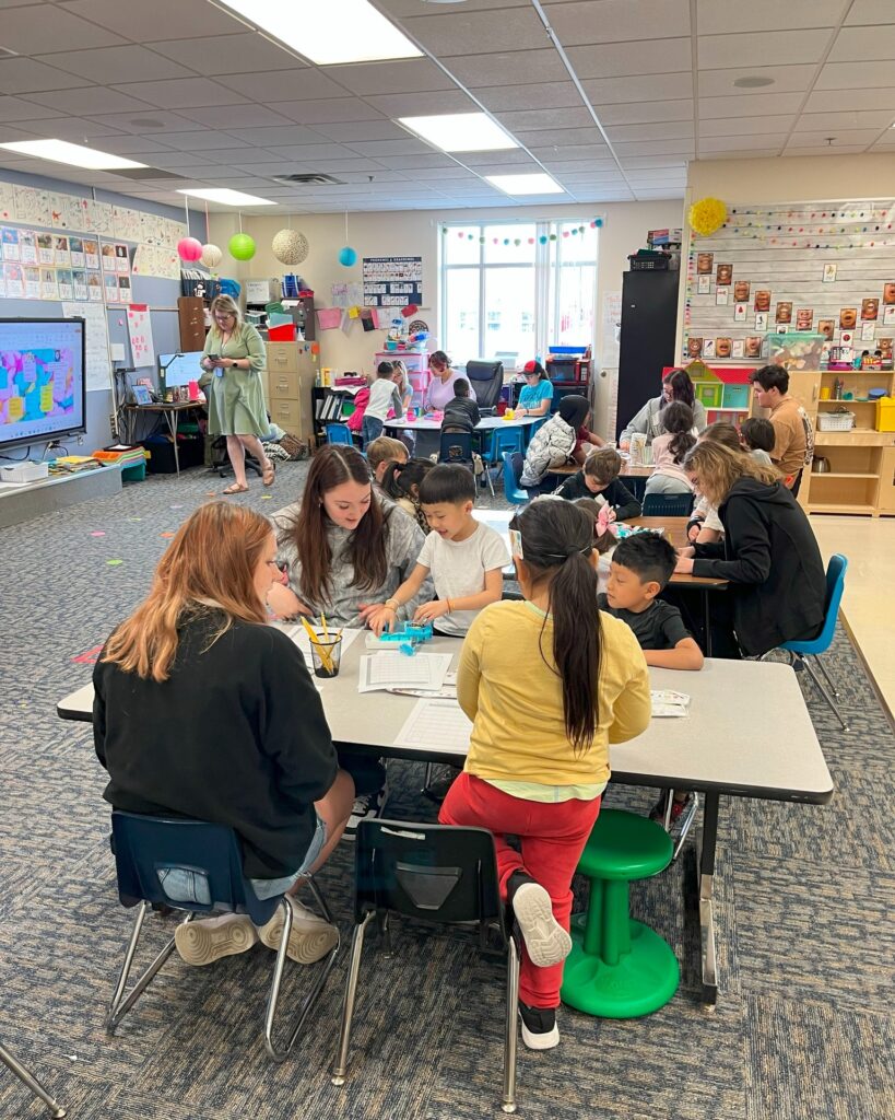 Classroom with high school students and elementary students at tables doing activities