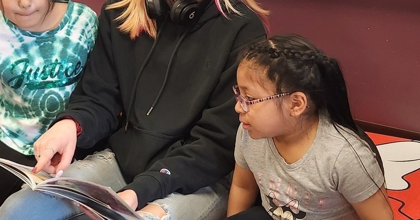 High school student reading to two elementary students