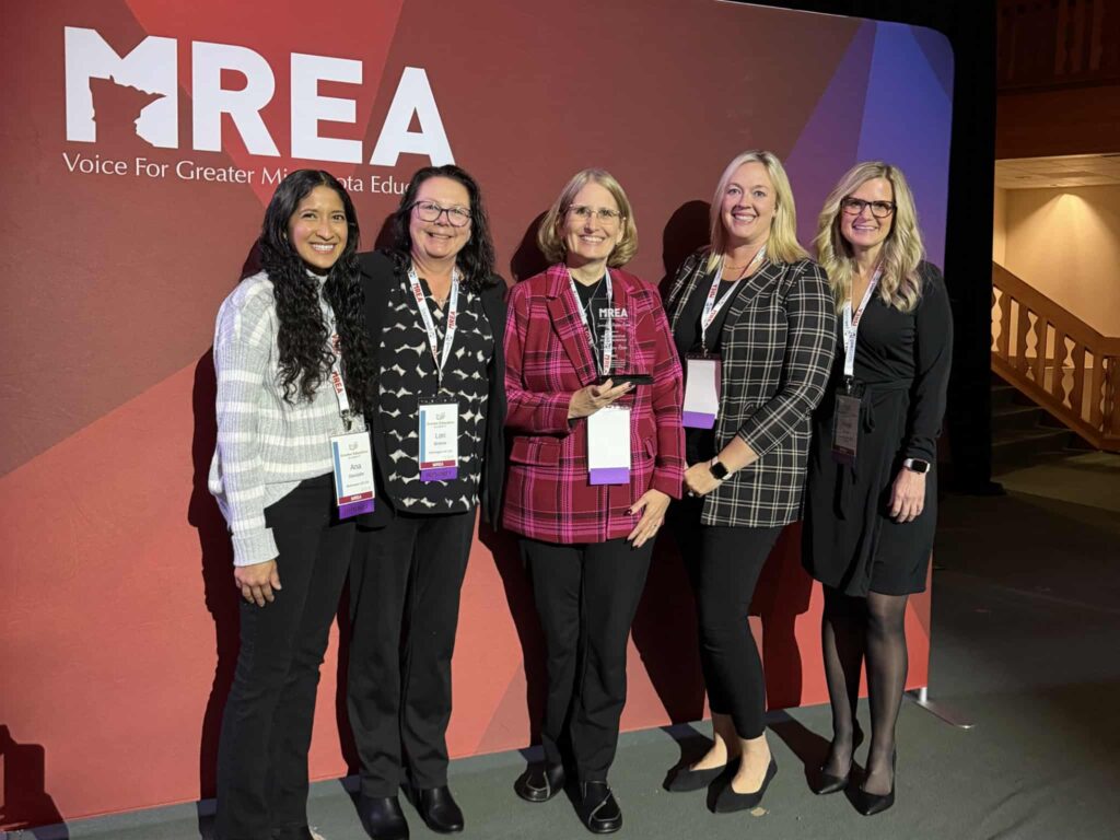 5 Prairie Elementary Staff holding the award under the MREA sign