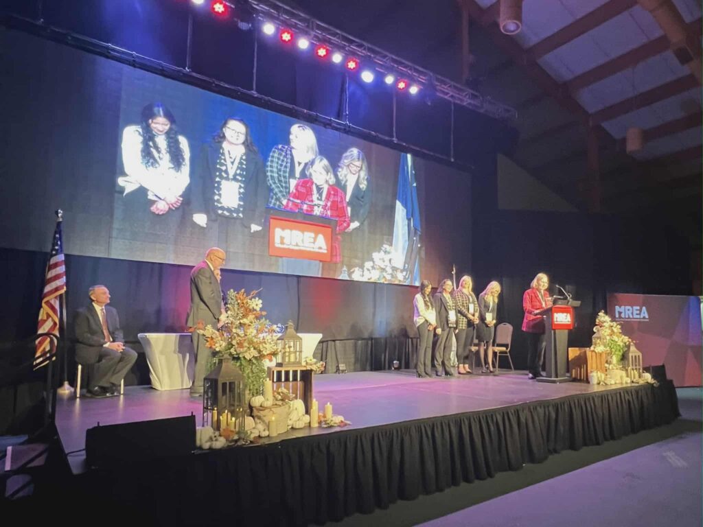 Mrs. Doeden speaking on stage with other staff to receive award