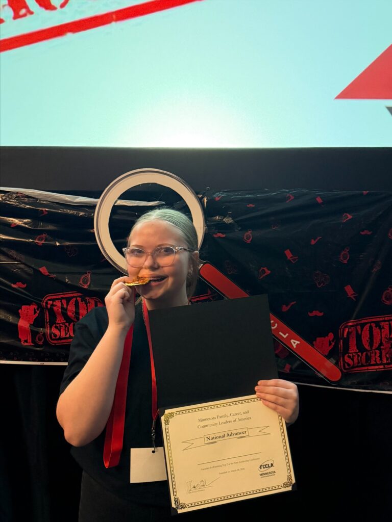 Student holding certificate biting gold medal