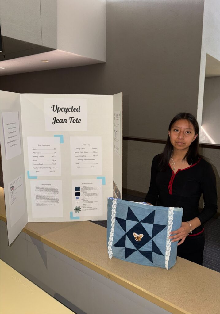 Student next to display board Upcycled Jean Tote and holding the tote